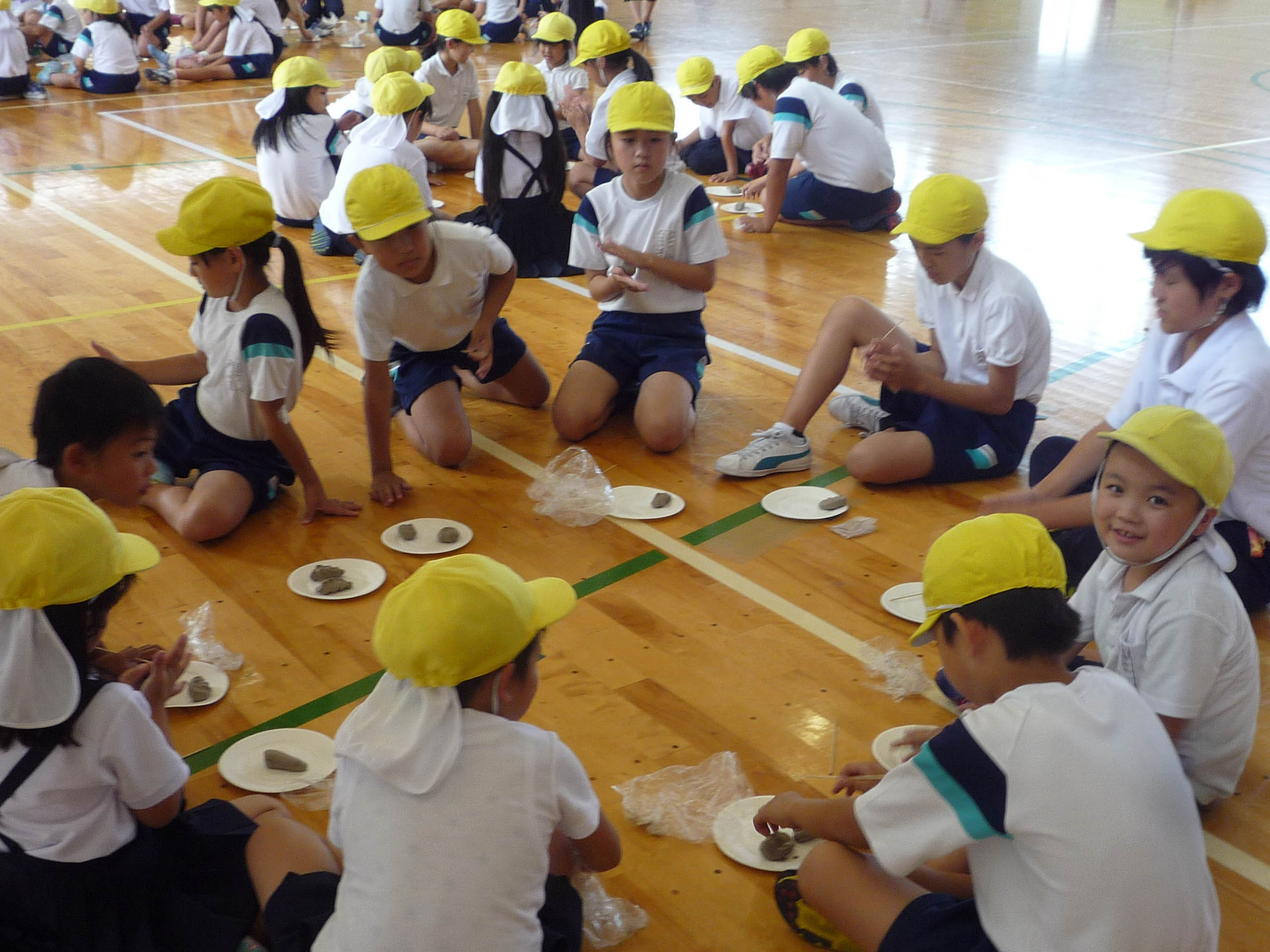 体育館で土を握る子どもたち