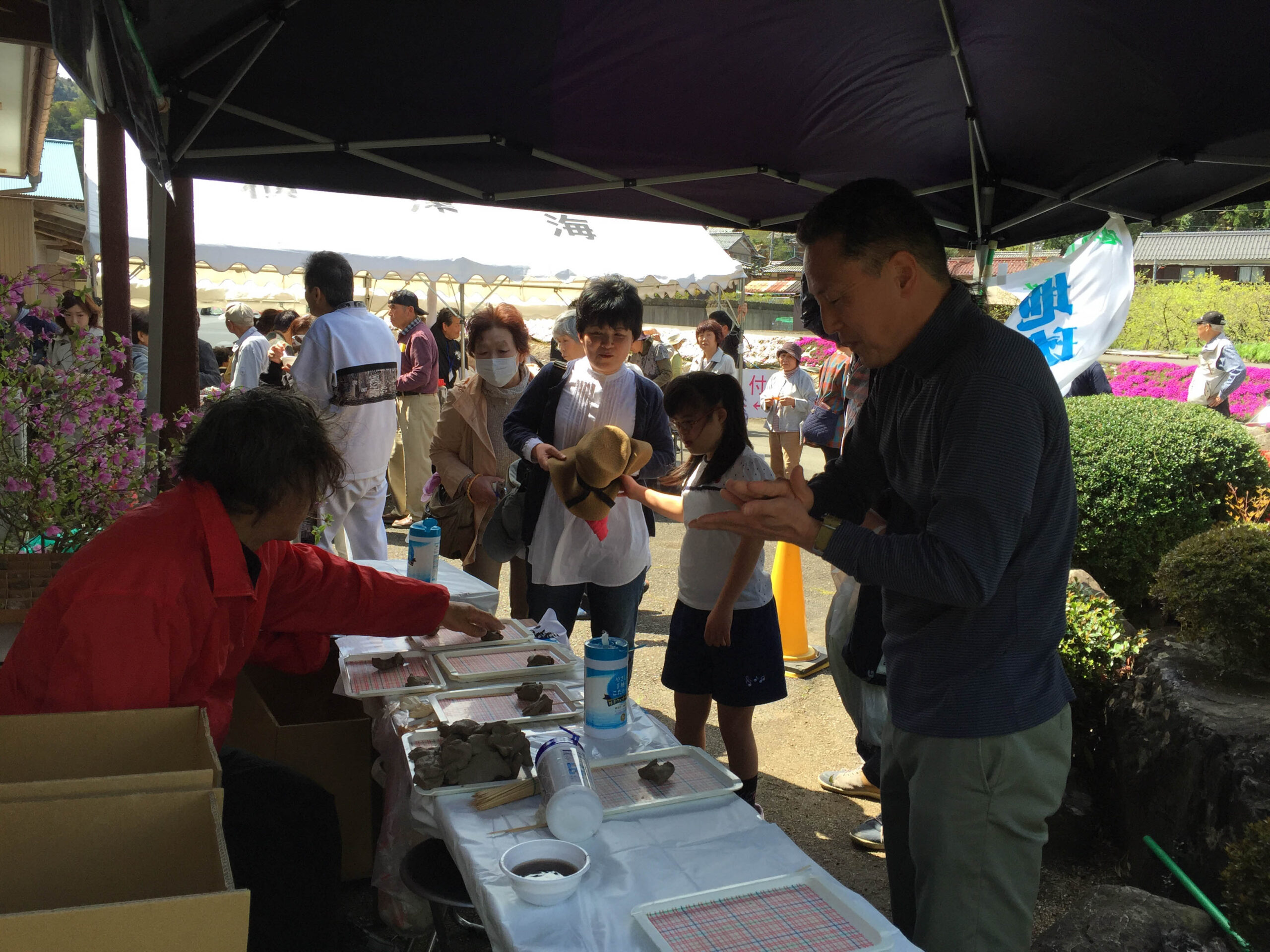 屋外のイベントで土を握る参加者