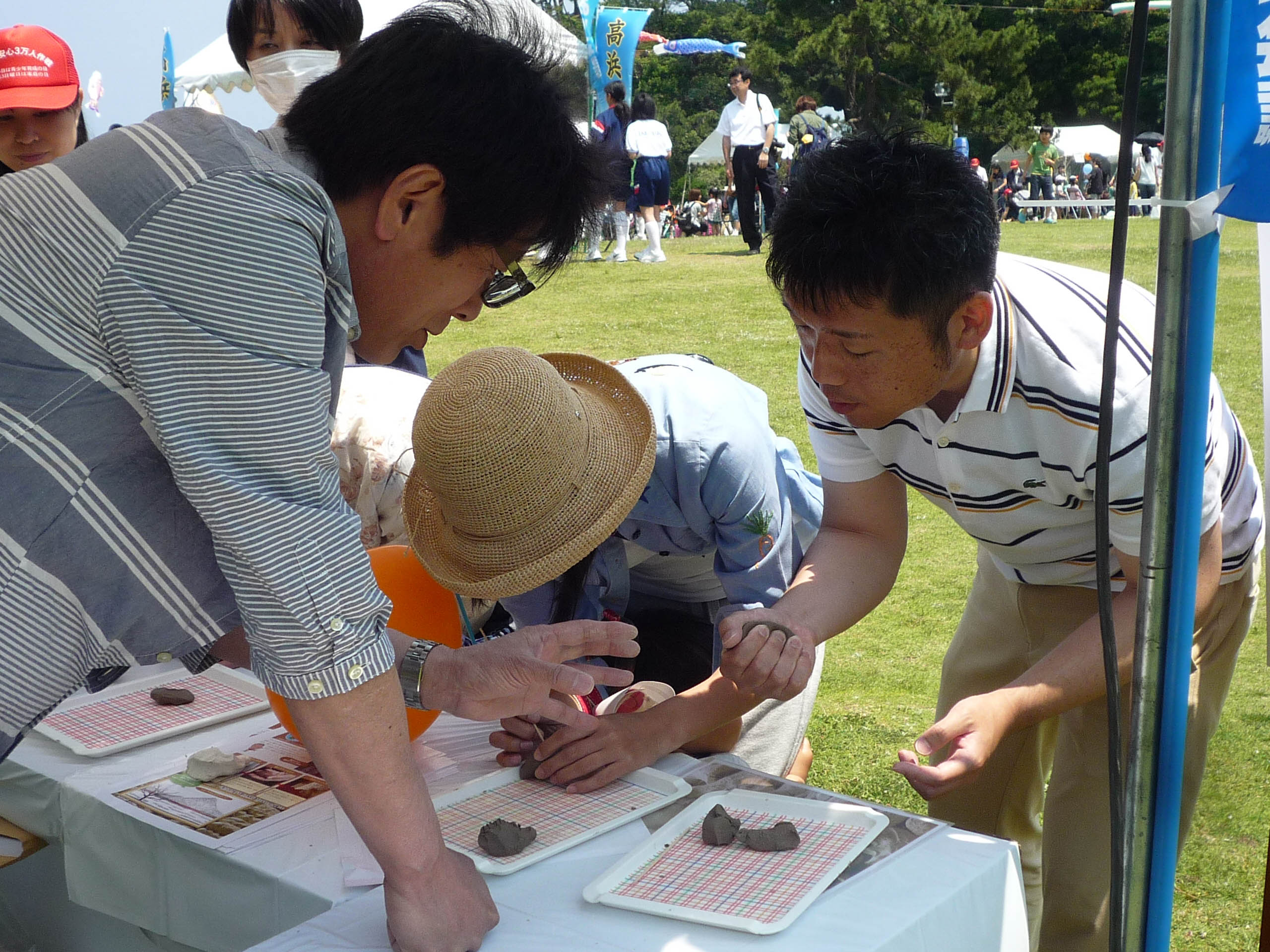屋外で土を握る参加者を支える人々