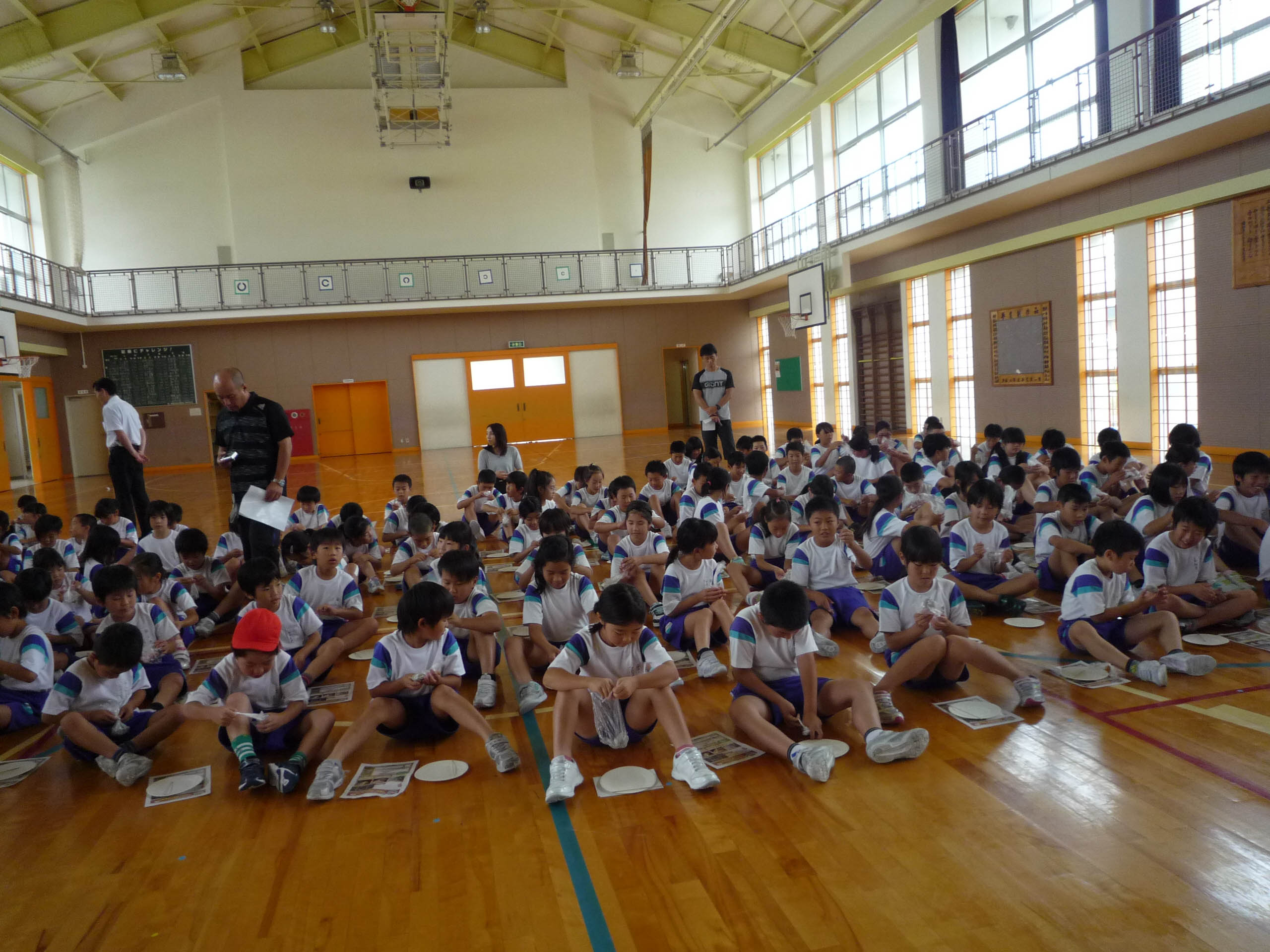 体育館で土を握る大勢の子どもたち