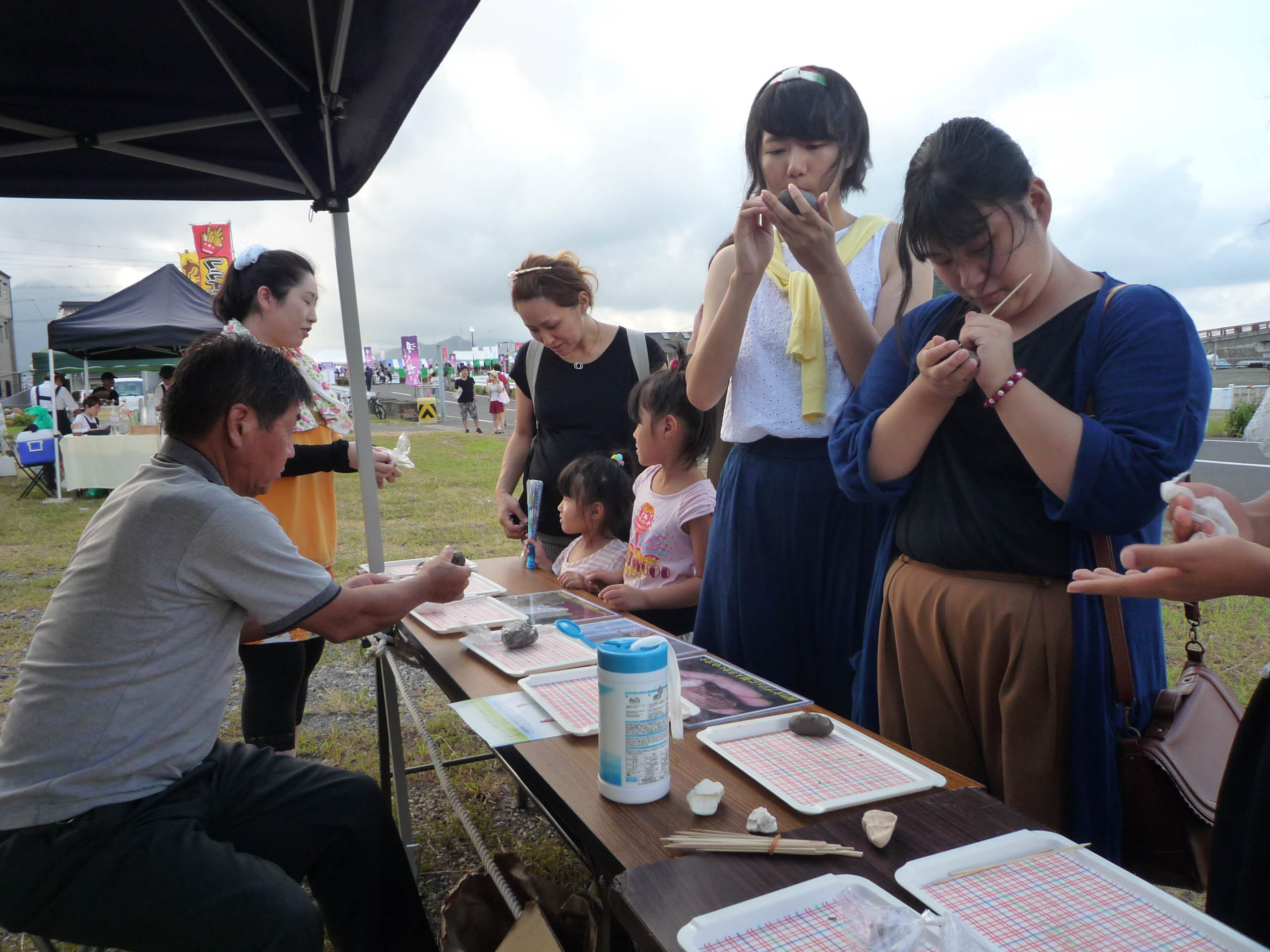 屋外イベントで土を握る参加者